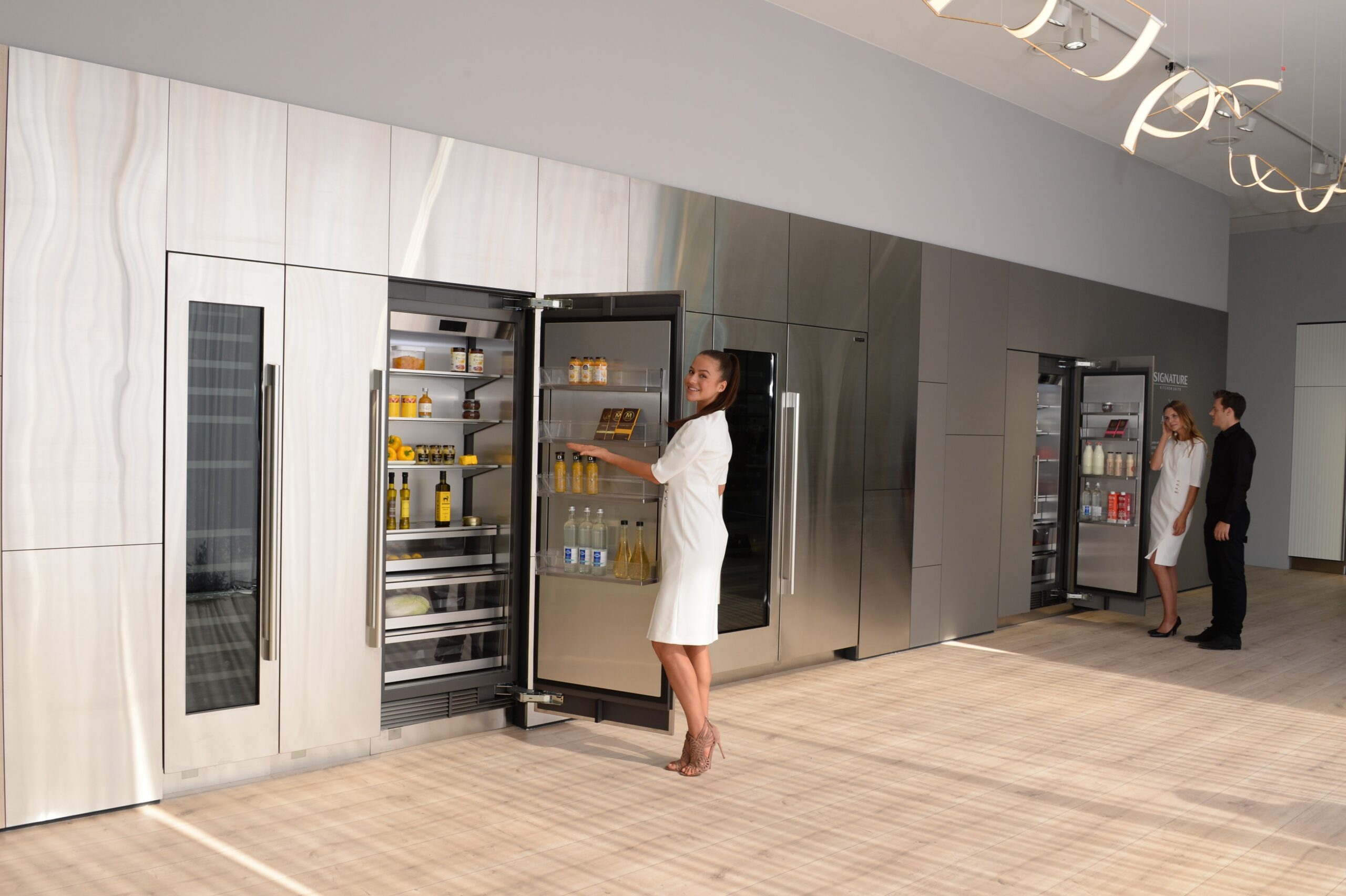 A close view of a refrigerator in the LG Signature Kitchen Suite display zone, a model is opening the fridge door.