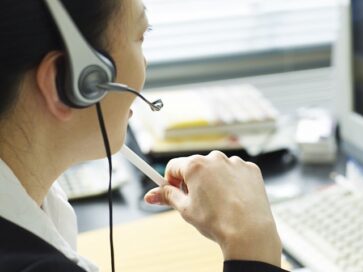 A woman taking a call at her computer while wearing a headset