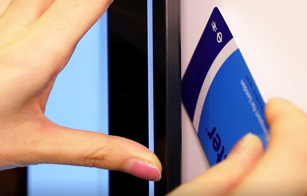 A woman uses her London transportation card to demonstrate just how thin the gap between the wall and the LG GX Gallery TV is