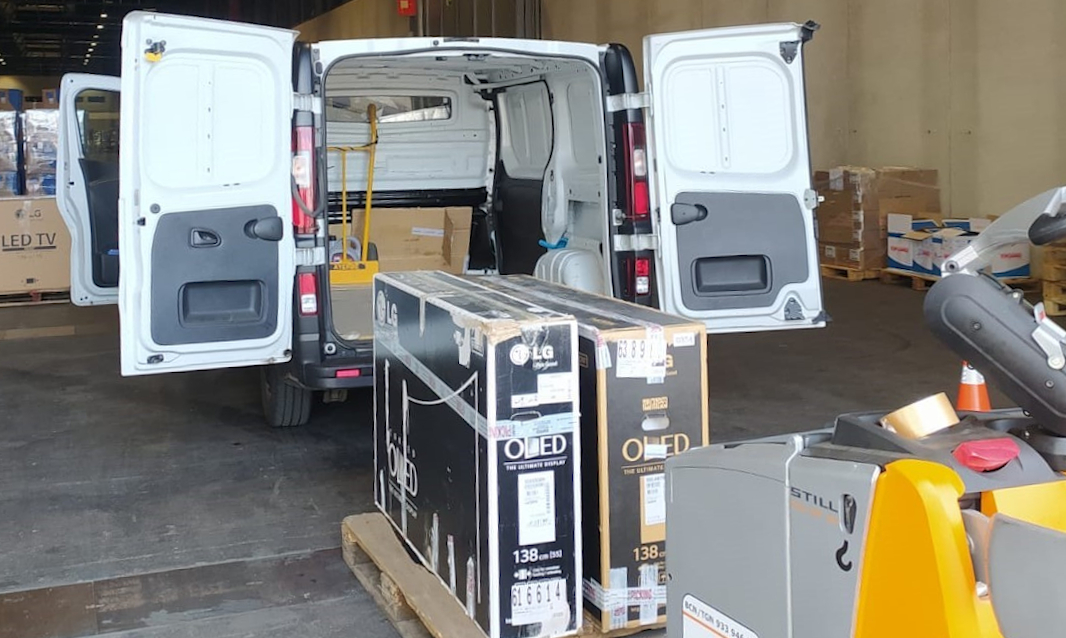 LG OLED TVs being loaded into the back of a van