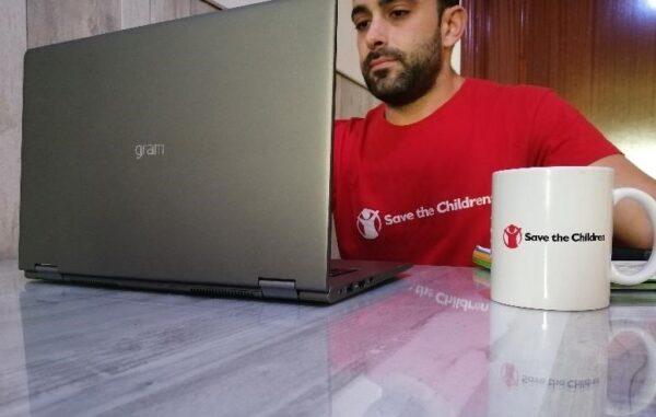 Un hombre que usa el gramo LG junto a una taza que muestra el logotipo de la organización Save the Children