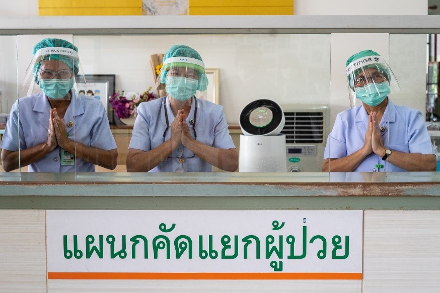 Three medical workers showing their gratitude in front of an LG PuriCare air purifier