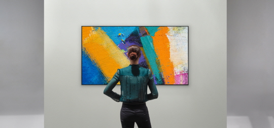 A woman admiring the LG GX Gallery series TV