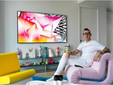 Karim Rashid sits next to the LG GALLERY DESIGN TV which is displaying his painting, DREAMSKAPE