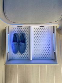 A look at the shoe storage box located below the seats of the IONIQ Concept Cabin, with it open and holding a pair of slippers with room for one more