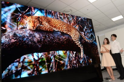 A wide image of two people looking at the LG MAGNIT displaying a magnificent leopard in awe, the shot showing just how large the display really is