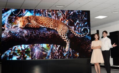 A front view of the LG MAGNIT’s screen displaying a majestic leopard with a man and woman posing beside it