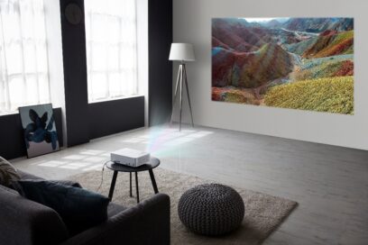 LG CineBeam stands on a small living room coffee table as it delivers vibrant images of a mountain forest in the room’s bright conditions