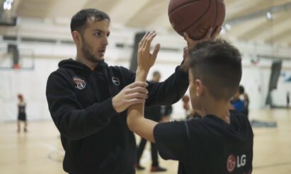 A basketball expert coaching an attendee on how to improve his game during the LG Athletes of Tomorrow program