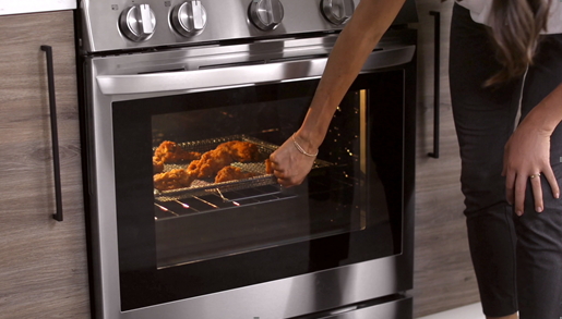 A woman knocks on the door of her LG smart oven via InstaView to check on her meal’s cooking progression
