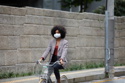 A woman on a bicycle wearing LG PuriCare™ wearable Air Purifier