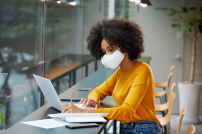 A woman wearing LG PuriCare™ wearable Air Purifier while working indoor