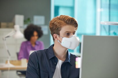 A man in an office wearing LG PuriCare™ wearable Air Purifier