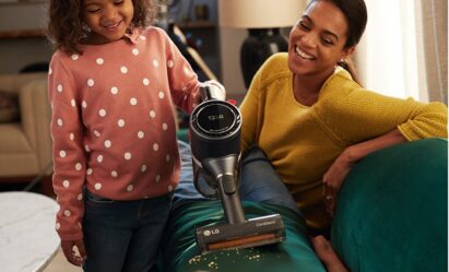 A mother watches on as her daughter uses LG CordZero A9 to vacuum the living room sofa