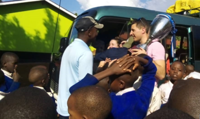 FC Cambounet being greeted at an elementary school in the village of Mbokomu, Tanzania, where they donated educational, technological and sporting equipment.