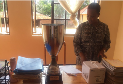 A Tanzanian teacher places the school's new LG CineBeam projector on her desk beside FC Cambounet's trophy.