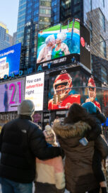 A family pause while walking through Times Square to watch the documentary on LG's giant commercial display.