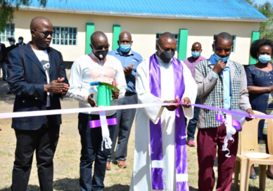 Father Joseph Mutuku cutting the ceremonial ribbon at the launch event of the project involving the construction of multiple facilities at Kyumbi Primary School in Machakos County.
