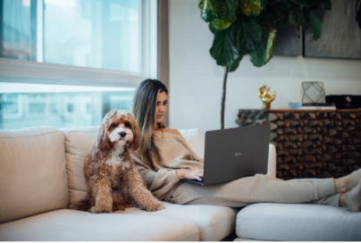 A woman working comfortably with the slim and light LG gram on her living room sofa with her dog by her side.