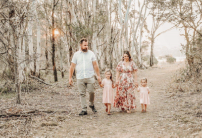 A family of four walking hand-in-hand through an Australian forest that has been ravaged by one of last year’s bush fires.