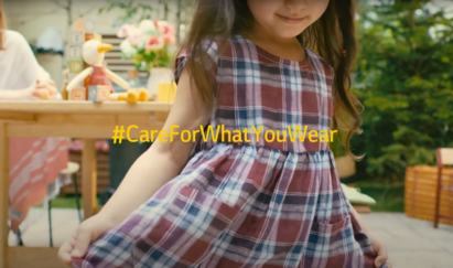 A little girl wearing a cute checkered dress smiling with the Care For What You Wear hashtag overlapping.