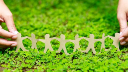 A person holding a paper chain family on a bed of grass.