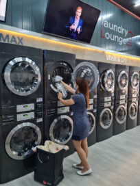 A woman is putting laundry into dryer at Laundry Lounge.