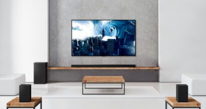 The LG Soundbar sitting on a wooden shelf below a wall-mounted LG TV complements the TV’s sound while perfectly blending into the modern room's interior