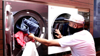 A man putting laundry into the LG washing machine so that they are fully sanitized and hygienic before being donated to local beneficiaries