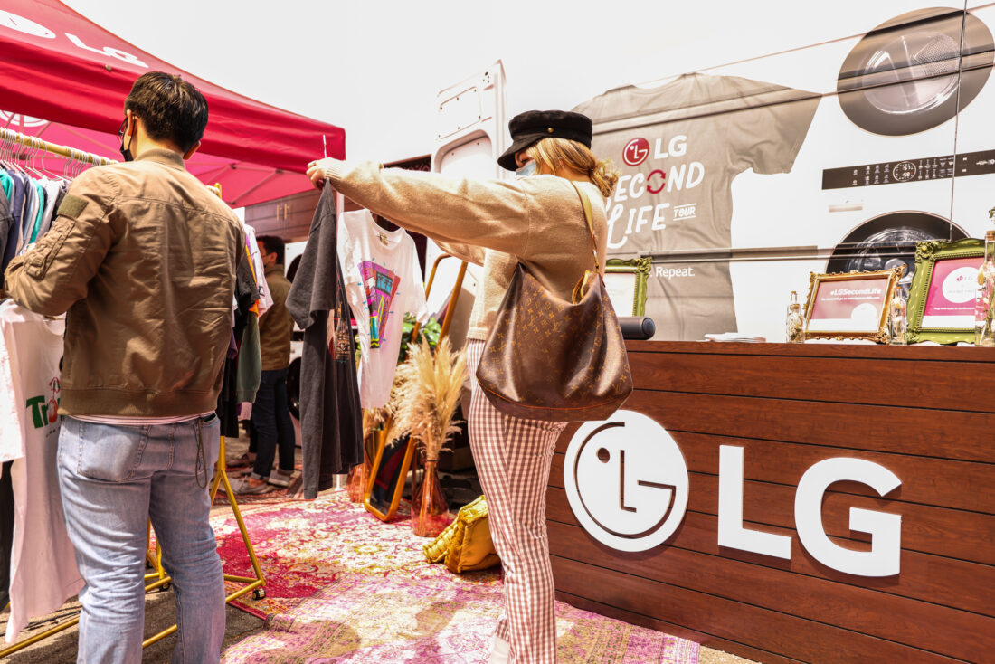 A woman carefully selecting between two shirts she discovered at the venue of The Second Life Campaign