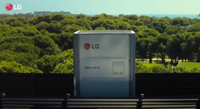 A photo of the LG Multi V Outdoor Unit installed outside a building with a sprawling forest in the background.