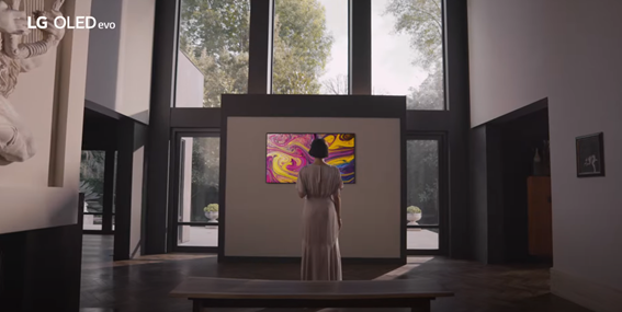 A woman admiring a vivid painting being displayed on an art gallery’s LG OLED TV
