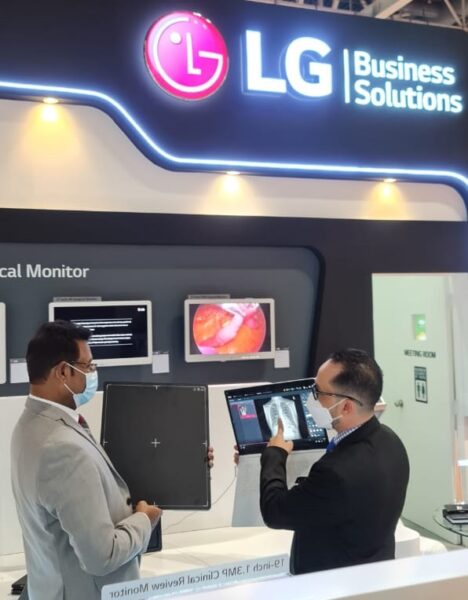  A scenery of demo shop. A person is holding a Digital X-Ray Detector, while another is giving a product guideline