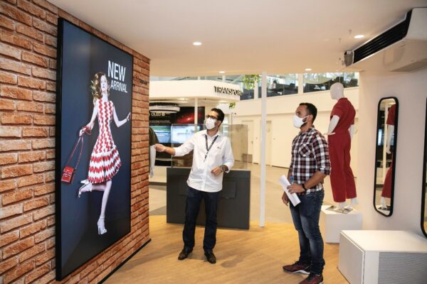 Two men admiring LG signage as it displays a fashion model in a white and red patterned dress.