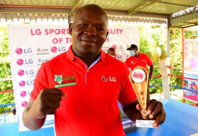 A photo of boxer Elly Ajowi making a proud fighting pose while holding his LG trophy