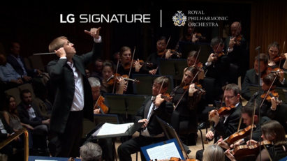The conductor and violinists of the Royal Philharmonic Orchestra during a performance with the logos of LG SIGNATURE and the orchestra above