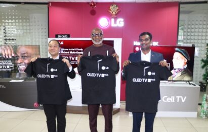 Nigeria’s Richard Mofe-Damijo holds up an LG OLED TV shirt with two LG representatives.