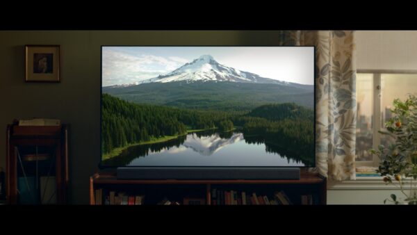 LG's TV displays a beautiful mountain, forest and lake inside a living room.