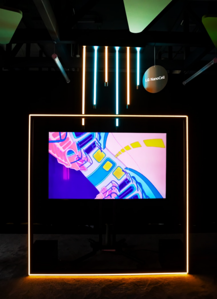 “Fission Fantasy” by Alberto Luango, which depicts the inside of a colorful subway train, displayed on LG NanoCell TV with neon lighting hanging above