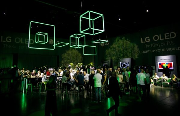 A wide view of the LG 2021 TV launch event in Israel with cubed green neon lighting hanging above a room full of people.