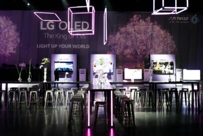 The empty hall used for the launch of LG’s 2021 TV lineup in Israel, with LG’s TVs in the background and neon lighting hanging above.
