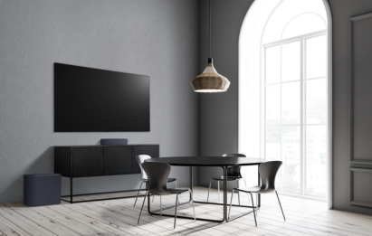 The black LG Éclair and subwoofer placed below a wall-mounted LG TV to effortlessly blend into a grey contemporary living space