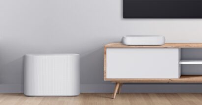 Close-up shot of the white LG Éclair on a wooden console with its subwoofer placed on the floor by its side