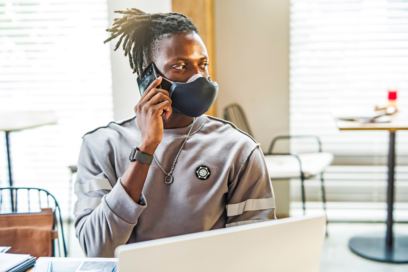 A man using his smartphone without removing LG PuriCare Wearable thanks to the clearness of VoiceOn technology.