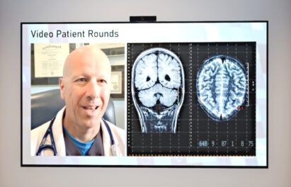 An image of video patient round - A screen displaying a X-ray result and a doctor
