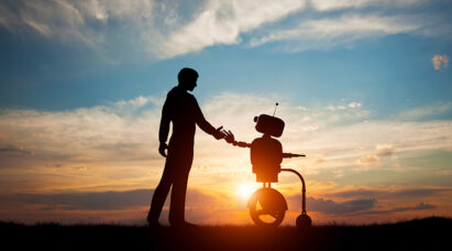 A human and a robot shaking hands during the sunset.