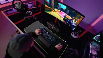 A gamer playing a game on an LG UltraGear gaming monitor connected to an LG UltraGear Gaming Speaker (model GP9)