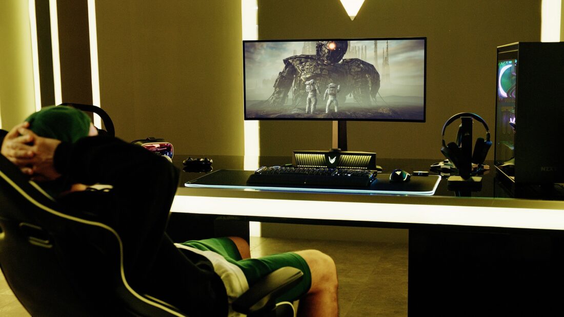 A gamer watching a game on an LG UltraGear gaming monitor connected to an LG UltraGear Gaming Speaker (model GP9)