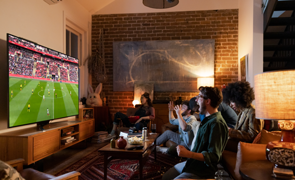 A group of friends in the living room watching a soccer game on one of LG's advanced TVs.