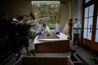 A film crew capturing the restoration process of removing the historic painting from its frame.